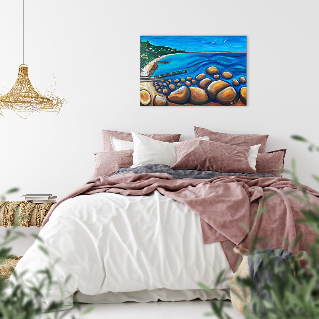 A Calm Day at Flinders Bay displayed above a bed with dusty-pink and white bedding.