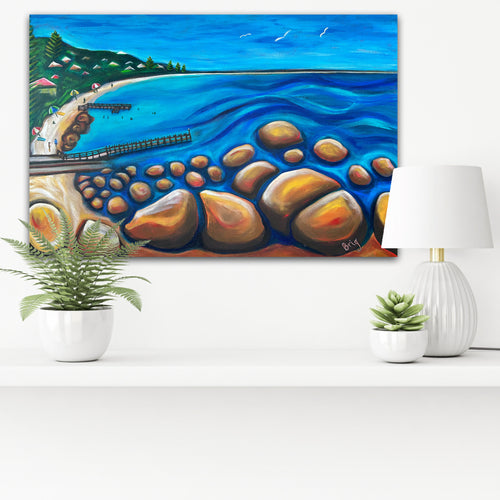 A Calm Day at Flinders Bay displayed above a white sideboard with potted plants and a white lamp.