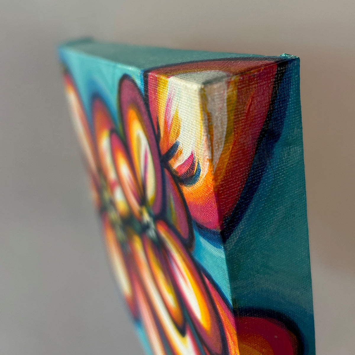 Close-up of a Joy of Colour canvas, showing the floral painting continuing around the edge in turquoise, pink, orange and yellow.