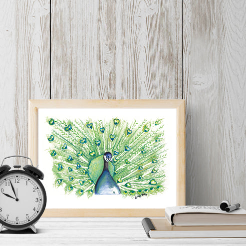 Framing mock-up of Peacock Watercolour with Hearts by Brigitte James in a light wooden frame beside a black clock and books.