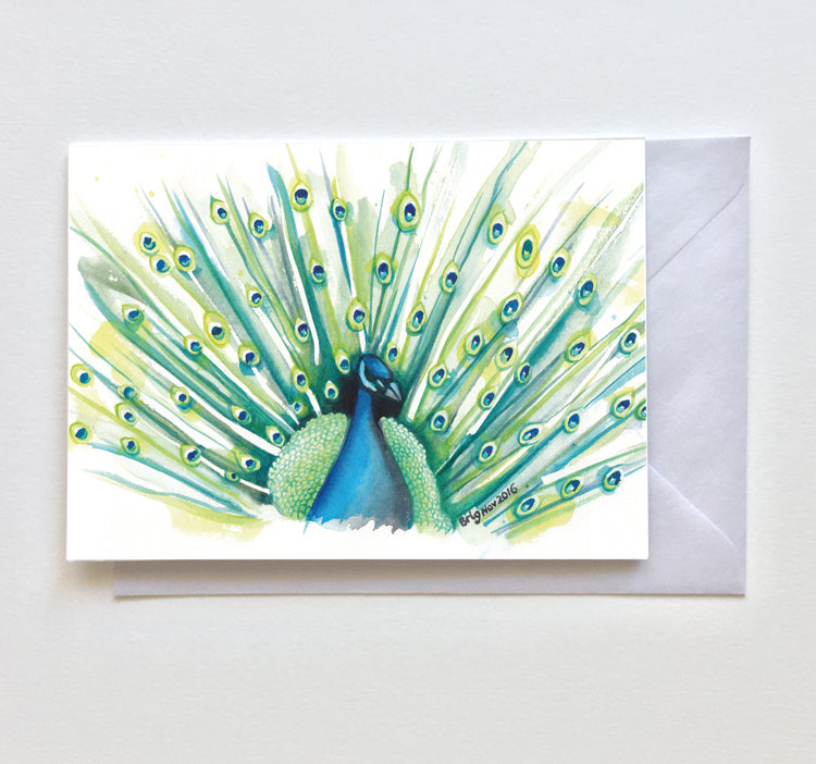 Peacock Watercolour greeting card by Brigitte James, showing fanned green and blue feathers, with an envelope behind it.
